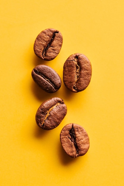 Granos de café tostados sobre fondo amarillo