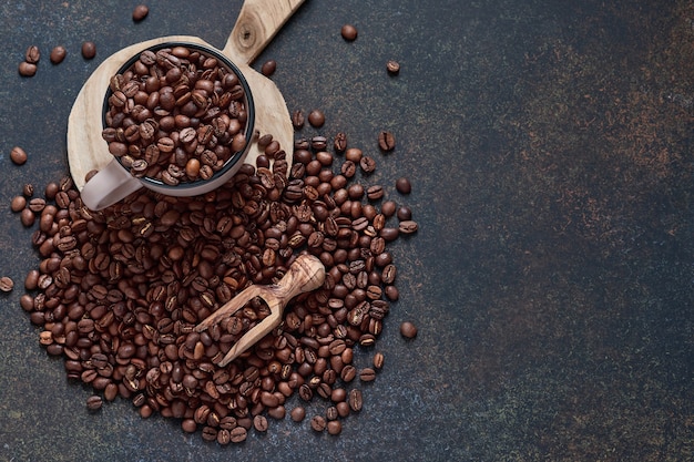 Granos de café tostados en taza y esparcidos cerca, café molido y azúcar de caña en una mesa marrón Vista superior con espacio para copiar texto.