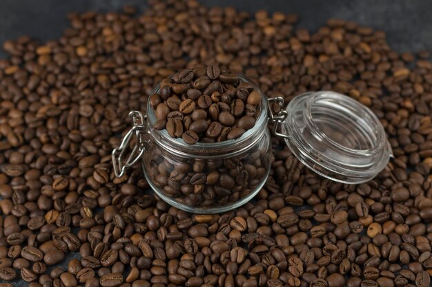 Foto granos de café en un vaso sobre fondo oscuro