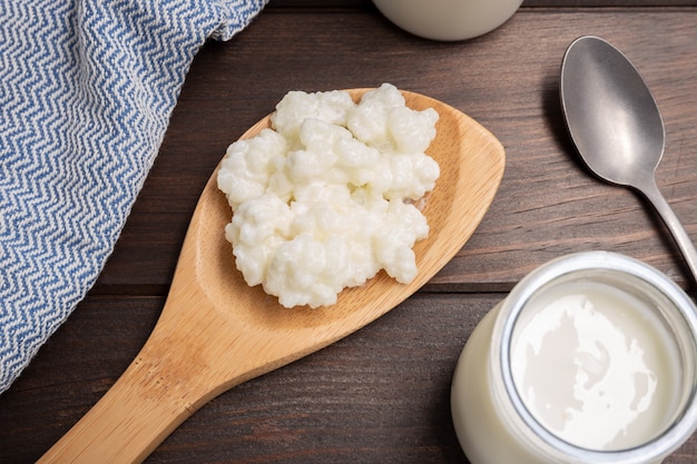 Granos de kéfir de leche en cuchara sobre mesa de madera