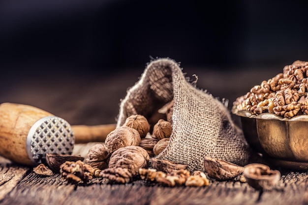 Granos de nuez nueces enteras en saco de arpillera y tazón vintage.