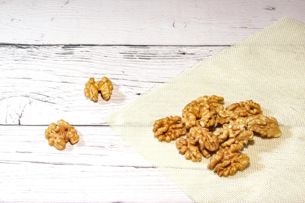 Granos de nuez en el tazón blanco sobre fondo de madera Granos de nuez secos sabrosos y saludables