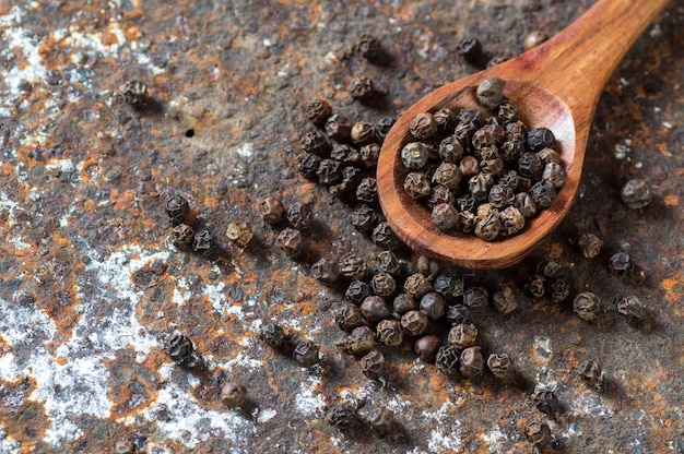 Granos de pimienta en cuchara de madera en textura