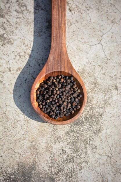 Foto granos de pimienta negra en una cuchara de madera