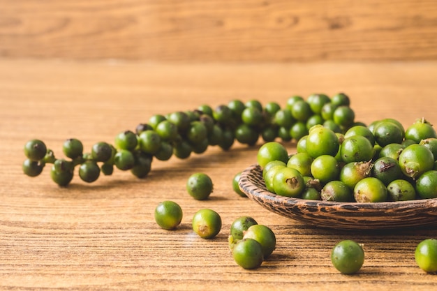 Granos de pimienta verdes sobre fondo de madera.