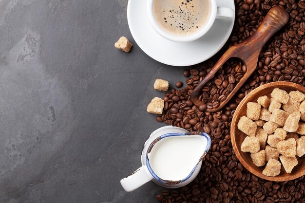 Granos de la taza de café y azúcar moreno en la mesa de piedra