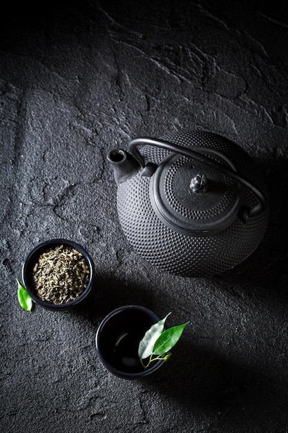 Granos de té verde en taza de té sobre roca negra