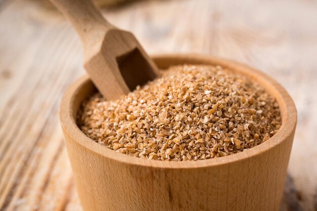 Granos de trigo en un recipiente sobre un fondo de madera Concepto de cereales dietéticos saludables