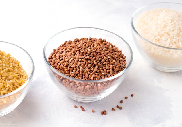 Granos de trigo sarraceno y arroz bulgur en cuencos de vidrio