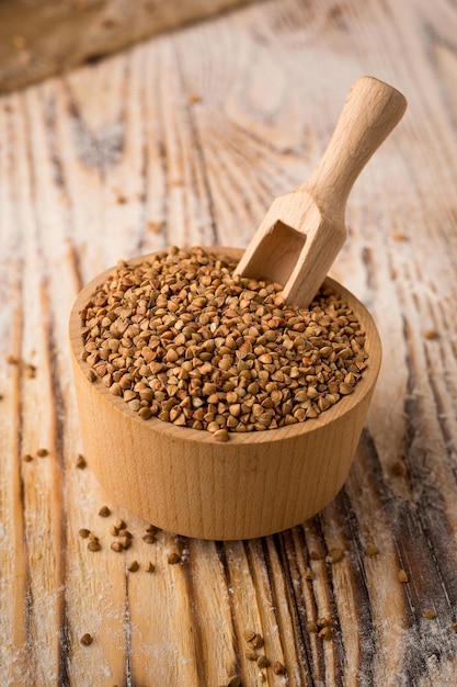 Granos de trigo sarraceno en un tazón sobre un fondo de madera Concepto de cereales dietéticos saludables