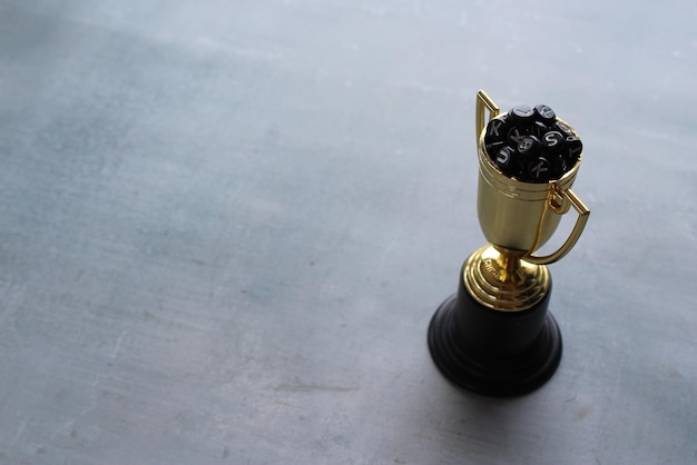 Grânulos de alfabeto dentro da taça de troféu de ouro com espaço de cópia Conceito de educação