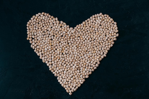 Grão de bico cru em forma de coração isolado em fundo preto proteína crua cultivada orgânica ingrediente saudável vegan comida nutritiva grão de bico cru