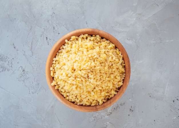 Grão de bulgur cru em uma tigela. Produto saudável, dietético, vegano e sem glúten. Conceito de alimentação saudável. Produto orgânico feito de grãos de trigo. Fonte de proteínas, fibras e gorduras naturais. Vista do topo. Foco suave