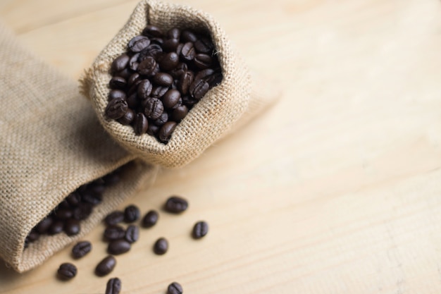 Grão de café no saco no espaço de cópia de mesa de madeira