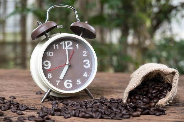 Foto grão de café torrado e despertador no chão de madeira na natureza para fins mylti
