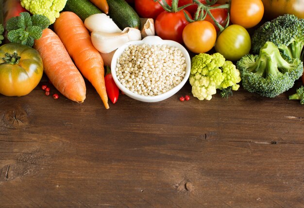 Grão de sorgo branco com legumes em uma mesa de madeira