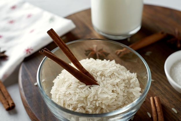 Grãos de arroz e paus de canela em uma tigela de vidro ingredientes para mingau de arroz com leite