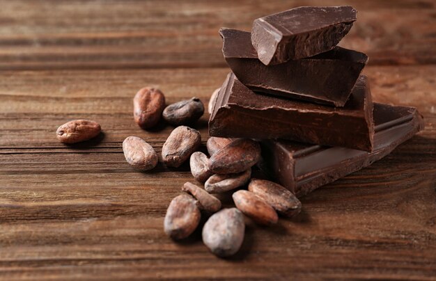 Grãos de cacau e pedaços de chocolate em fundo de madeira