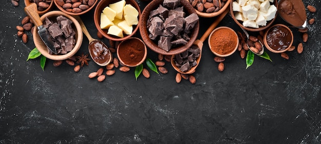 Grãos de cacau manteiga de cacau chocolate e cacau em pó em um fundo preto Vista superior Espaço para cópia grátis