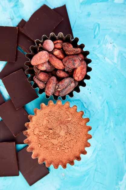 Grãos de cacau na mesa azul. Pedaços de chocolate amargo