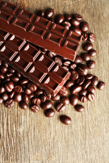 Grãos de café com cobertura de chocolate e chocolate escuro em fundo de madeira