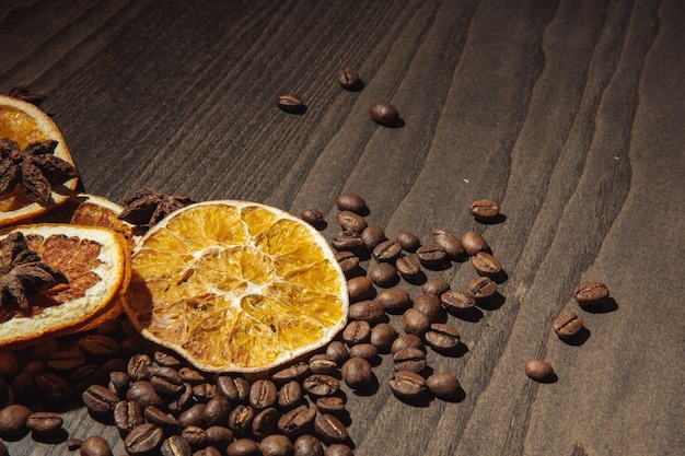 Grãos de café com laranja seca e canela em um fundo de madeira