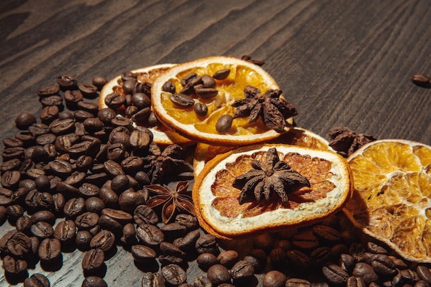 Grãos de café com laranja seca e canela em um fundo de madeira