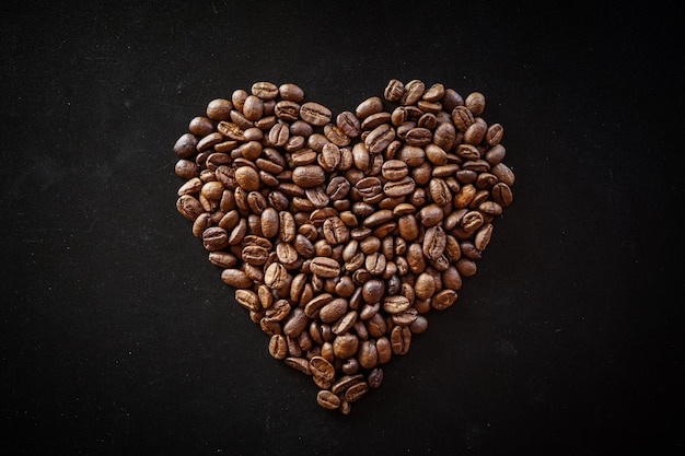 Foto grãos de café dispostos em forma de coração em fundo preto