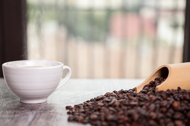 Grãos de café, donut e uma xícara de café em foto de perto