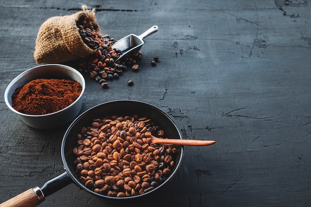 Grãos de café e café em pó em um fundo preto de madeira