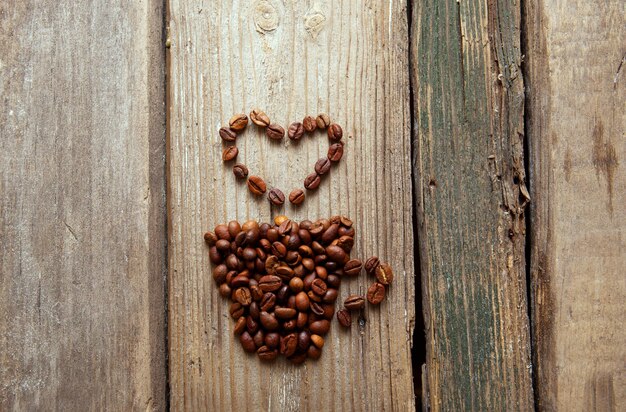 Foto grãos de café e copo no fundo de madeira