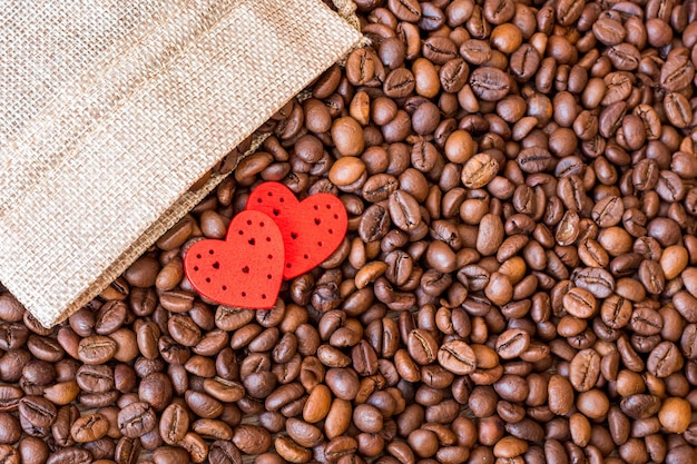 Grãos de café e corações vermelhos em uma mesa de madeira. Café é a bebida favorita