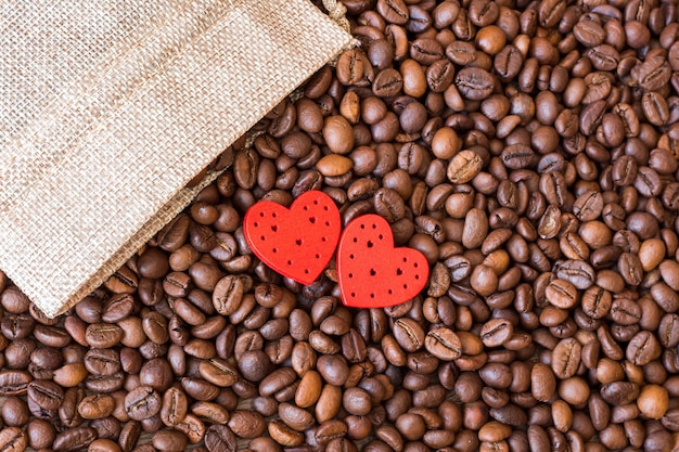 Grãos de café e corações vermelhos em uma mesa de madeira.