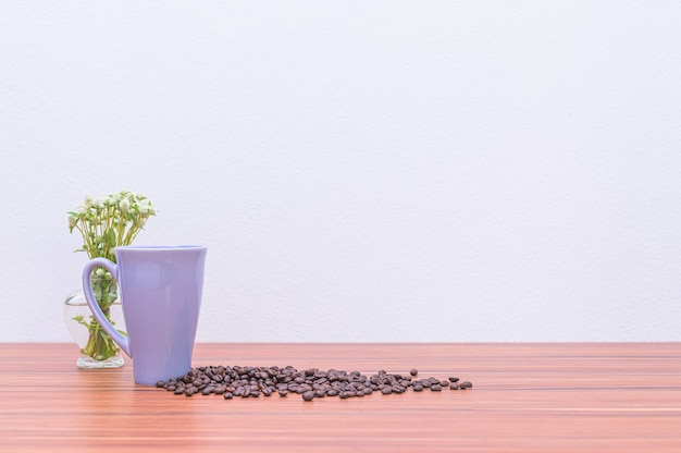 Grãos de café e vasos de flores na mesa