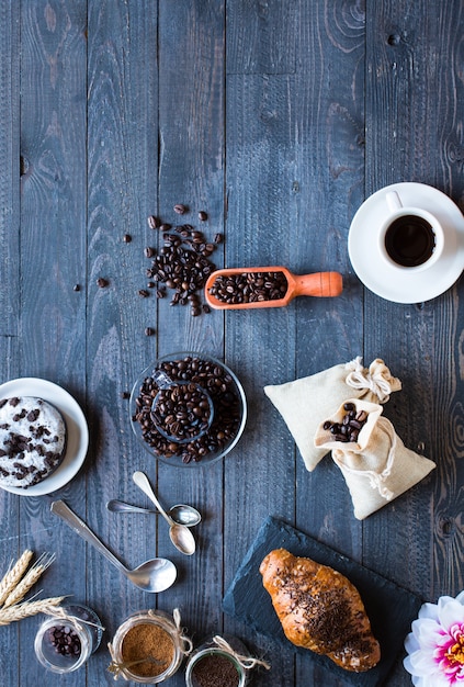 Grãos de café e xícara de café com outros componentes em fundo de madeira diferente.