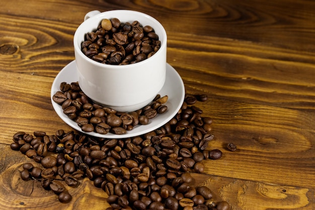 Grãos de café em copo branco na mesa de madeira