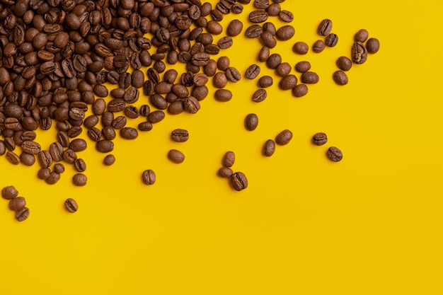 Grãos de café em um fundo amarelo, outros grãos espalhados, conceito