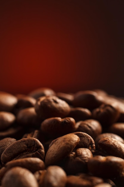 Foto grãos de café em um fundo escuro com um destaque vermelho no fundo closeup de grãos de café para uma cafeteria