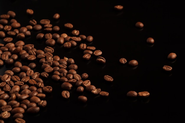 Grãos de café em um fundo preto Café em um fundo preto com reflexo