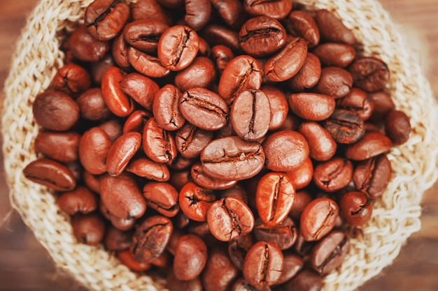 Grãos de café em um saco de estopa em uma superfície de madeira Contraste suave Grãos de café torrados aromáticos