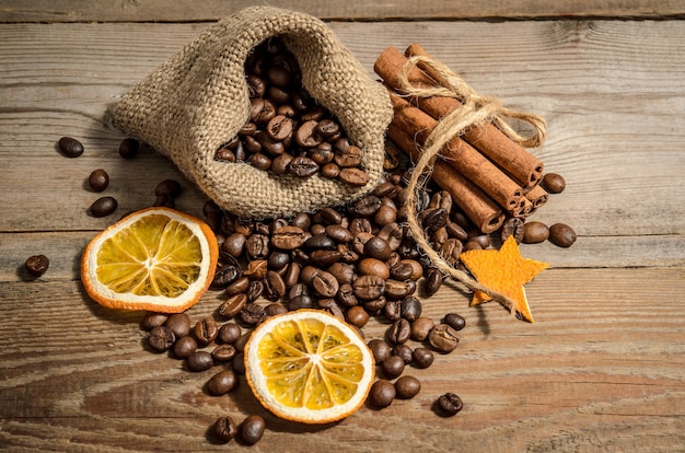 Grãos de café em um saco e canela em uma mesa de madeira