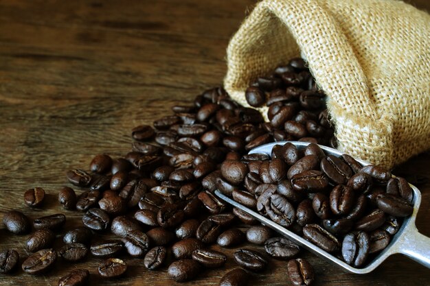 Grãos de café em um saco na mesa de madeira.