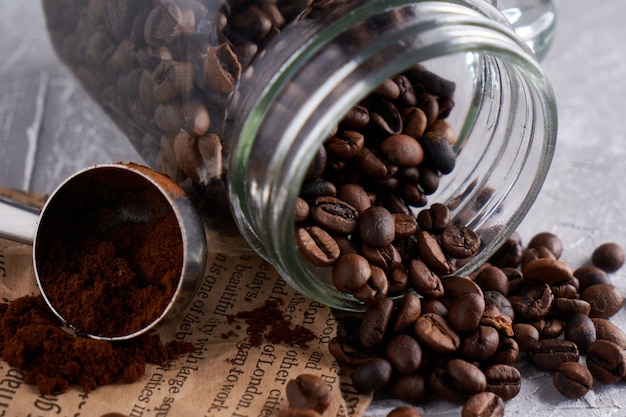 Grãos de café em uma jarra de vidro sobre uma mesa cinza