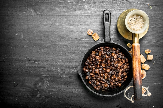 Grãos de café fritos em uma frigideira. No quadro negro.