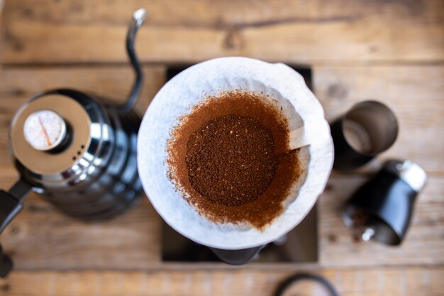 Foto grãos de café moídos em um funil. ritual de fabricação de café. fazendo café em casa. o café filtrado, ou transbordamento, é um método que envolve despejar água no café torrado