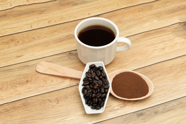 Grãos de café torrados, café moído, xícara de café, colher de pau com café torrado