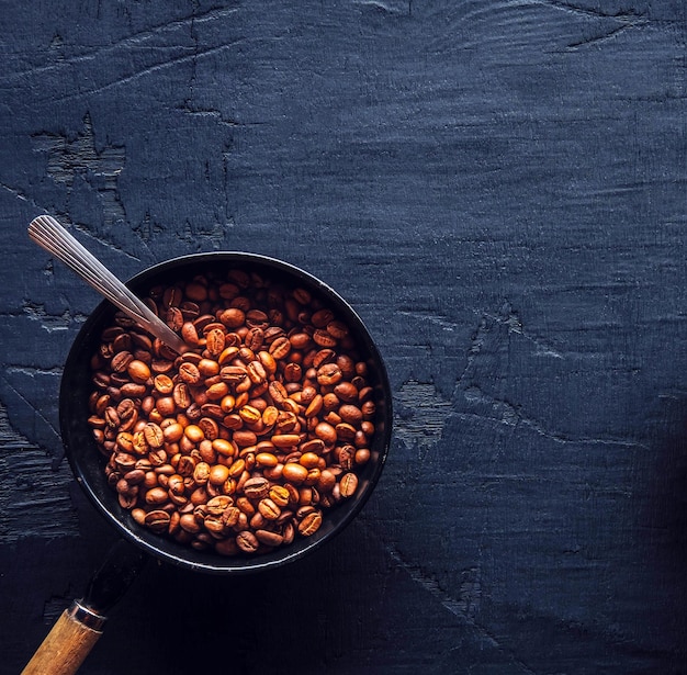 Grãos de café torrados castanhos claros na panela sobre fundo de madeira