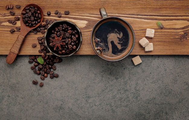 Grãos de café torrados com a configuração da xícara de café em fundo de pedra escura.