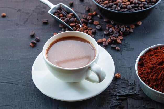 Grãos de café torrados com pó de café e xícaras de café.