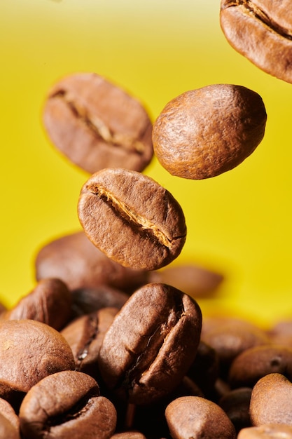 Grãos de café torrados isolados de perto no caminho de recorte de fundo amarelo